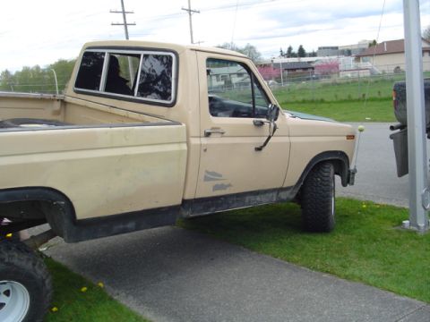 1985 Ford F-150 - Side view of a tan Ford F-150 pickup truck with a camper shell.