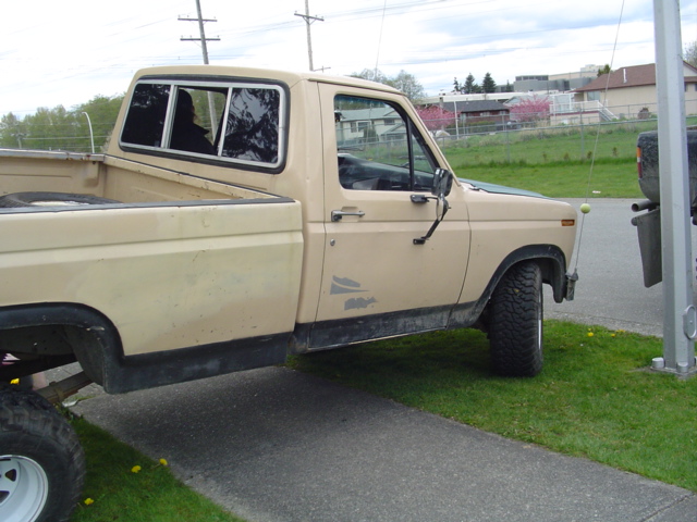 Tan Ford F-150 pickup truck, side view. The truck has a camper shell and aftermarket wheels