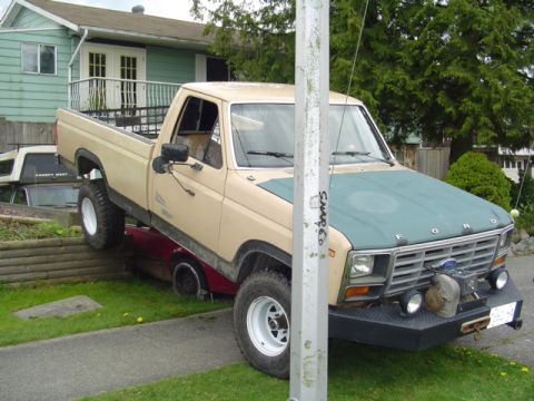 1985 Ford F-150 - This Ford pickup truck, likely from the early 1980s, is parked precariously on top of another vehicle.