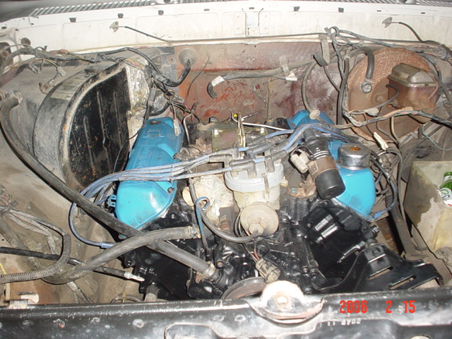 Engine bay with blue valve covers and various hoses and wires
