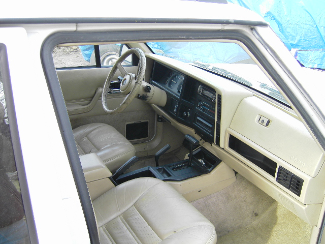 Beige leather interior of a 1984 Jeep Cherokee, showing dashboard, steering wheel, and seats