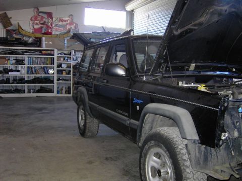 1998 Jeep Cherokee - A black Jeep Cherokee is parked in a garage with its hood and rear hatch open, showing its interior and engine bay.