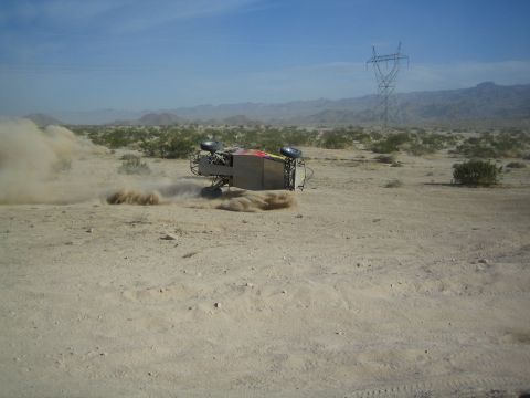 Off-road buggy rolled onto its side throwing up dust in the desert
