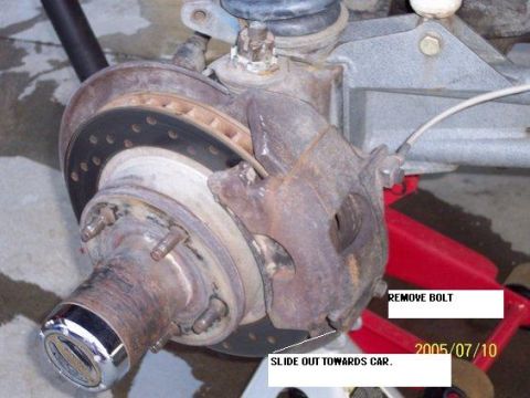 1985 Ford Bronco - Close-up of a vehicle's front brake assembly, showing the caliper, rotor, and hub. Text annotations provide instructions for removal.