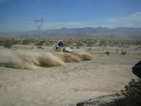 Off-road race vehicle barely visible in a large cloud of desert dust