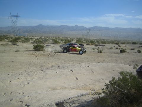 Red and yellow off-road buggy racing across the desert near power lines