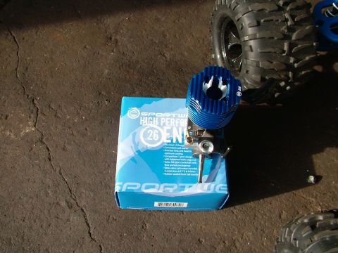 1994 Ford Bronco - A blue 26cc high-performance engine for an RC car sits on its packaging, with a large tire visible in the background.