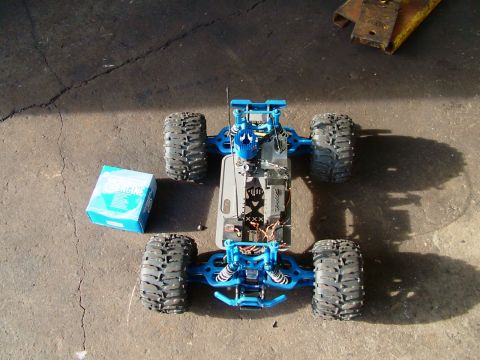 1994 Ford Bronco - A blue remote control monster truck is disassembled on a concrete surface, with its internal components exposed.