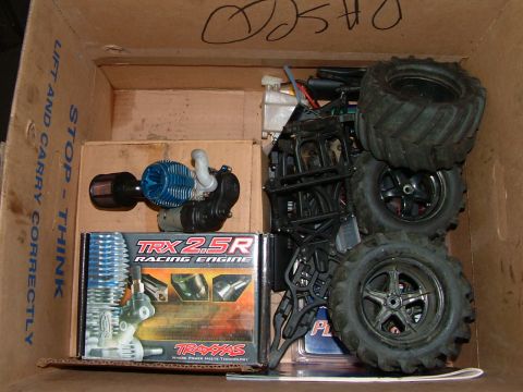 1994 Ford Bronco - RC car parts, including a Traxxas engine and chassis, are packed in a cardboard box.