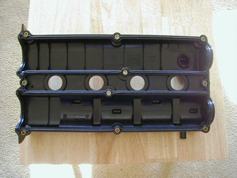 1994 Ford Probe - This is a close-up of a black engine valve cover, likely a replacement part, shown on a wooden background.