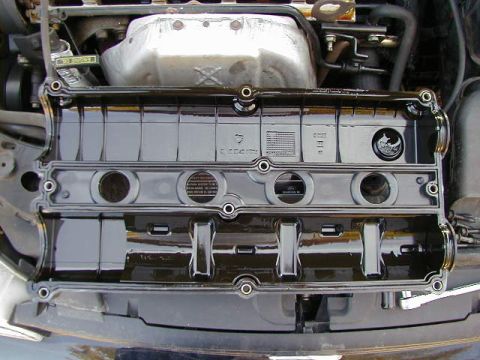 1994 Ford Probe - Close-up of an engine valve cover, revealing internal parts and oil residue.