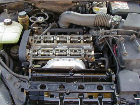 1994 Ford Probe - Close-up view of an engine bay, revealing internal components like the camshaft and spark plug wires, with the valve cover detached.