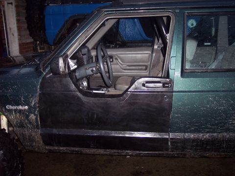 1993 Jeep Cherokee - Driver's side interior of a 1993 Jeep Cherokee with the door removed, showing the dashboard and seats.