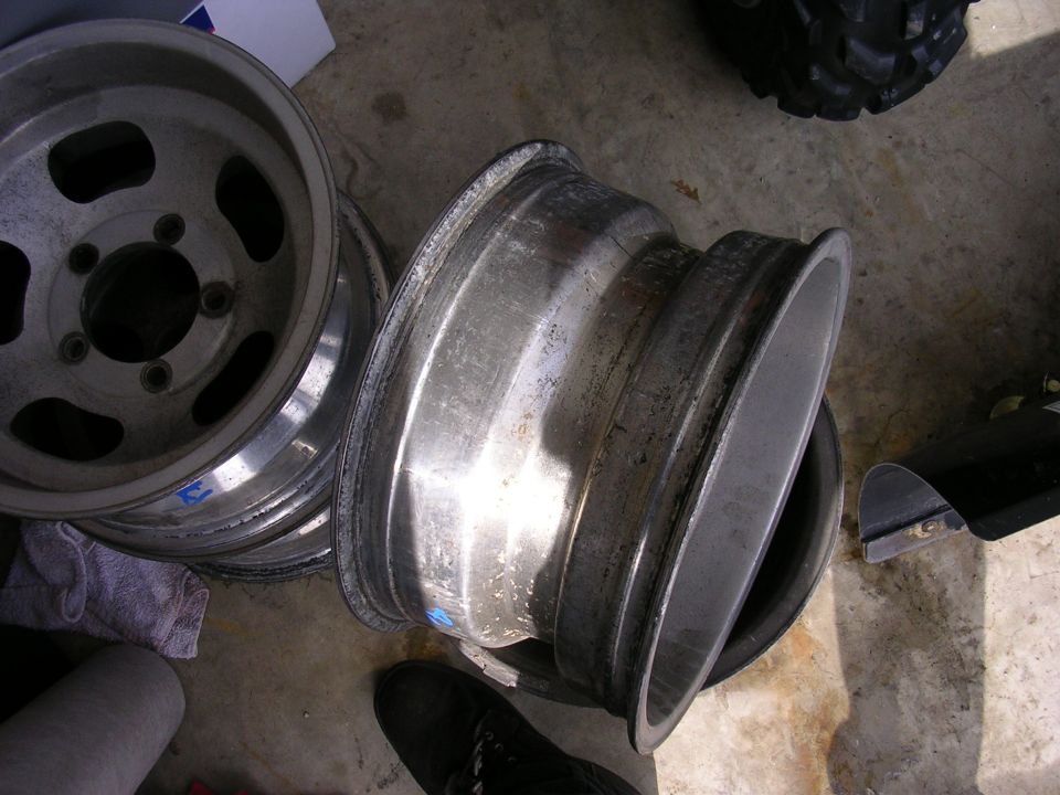 Stack of aluminum wheels, one in foreground is damaged