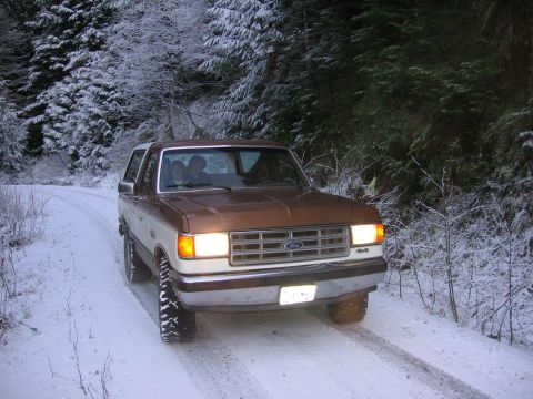 1987 Ford Bronco - A 1987 Ford Bronco navigates a snow-covered forest road.