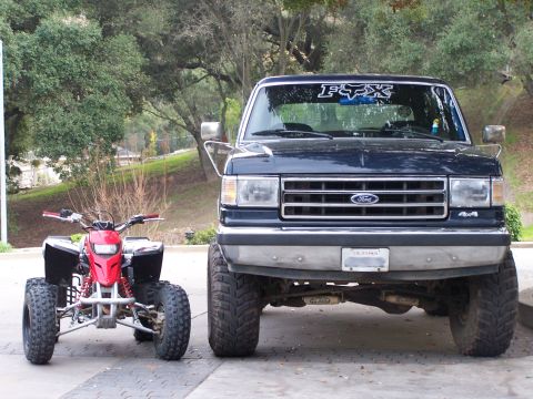 1991 Ford Bronco - A dark blue Ford Bronco from the late 1980s is parked next to a red ATV.