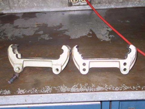 1997 Ford Taurus - Two tools for spreading brake calipers are shown on a workbench next to a red cable.