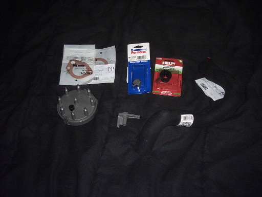 Flat lay of new auto parts including distributor cap, gaskets and blister-packed components