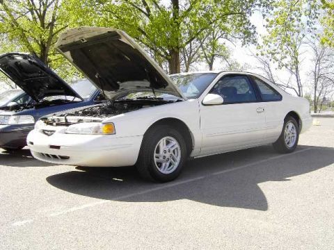 1996 Ford Thunderbird - A white 1996 Ford Thunderbird coupe is parked with its hood open, alongside another vehicle.