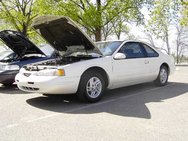 White 1996 Ford Thunderbird coupe, hood open, parked next to another car