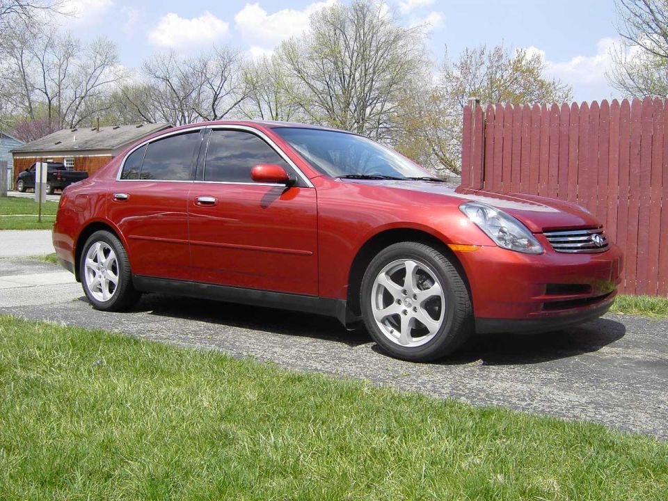 Red Infiniti G35 sedan, polished paint, 3/4 front view on driveway by red fence