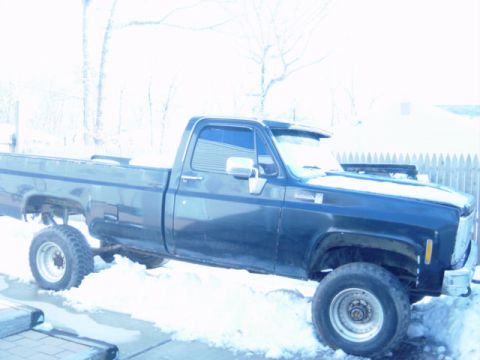 1987 Suzuki Samurai - A dark-colored pickup truck sits in the snow, partially obscured by winter weather.