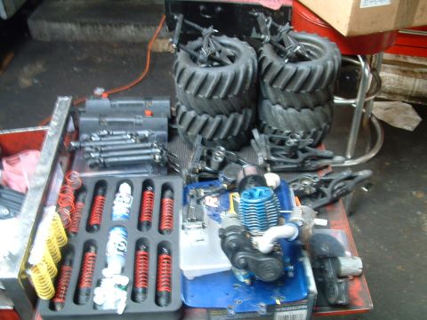 1994 Ford Bronco - Various parts for an RC car are laid out on a workbench, including an engine, shocks, and large tires.