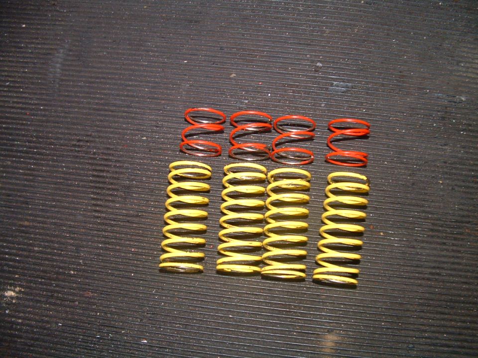 Set of red and yellow suspension springs laid out on a dark textured surface