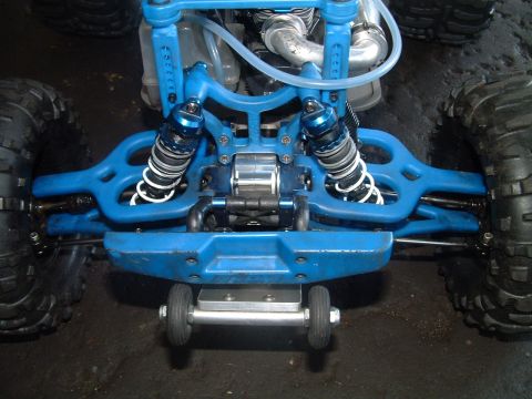 1994 Ford Bronco - The front suspension and large tires of a blue RC monster truck are shown up close.