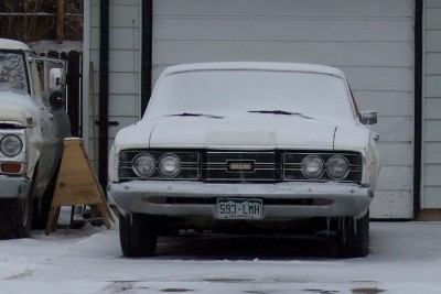 1972 Ford Ranchero - A white 1967 Mercury Cougar sits covered in snow, parked in front of a garage with icicles hanging from its bumper.