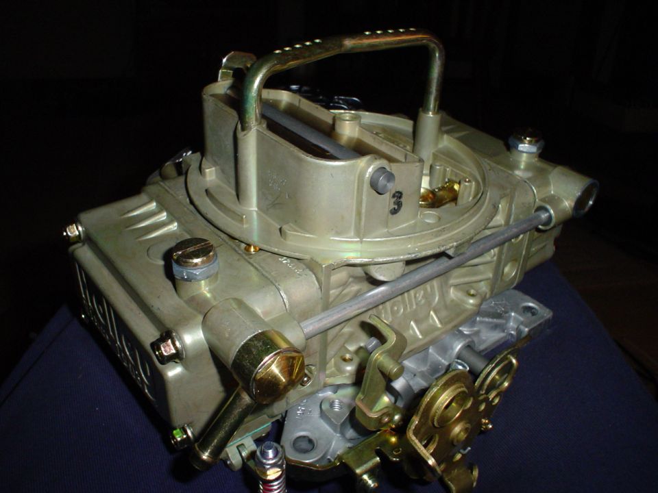 Gold Holley carburetor with a metal handle on top