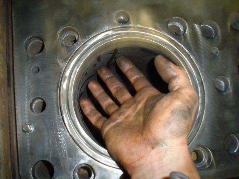 1966 International School Bus - A hand is placed inside a large engine cylinder, revealing the internal components and machining details.