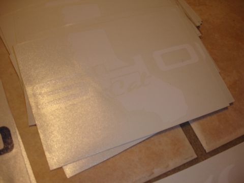 1993 Ford Taurus - A pile of stickers, some the shape of California, are stacked on a tiled surface.