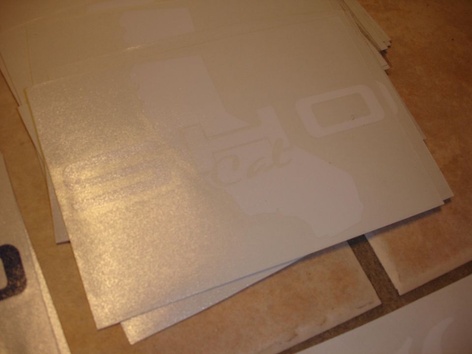 Stack of white stickers, some shaped like California, with 'Cal' visible on one