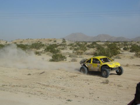 Yellow off-road race truck numbered 502 racing through desert dust