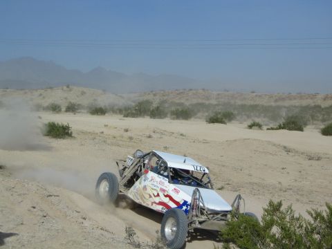 White off-road race buggy with stars-and-stripes graphics in the desert
