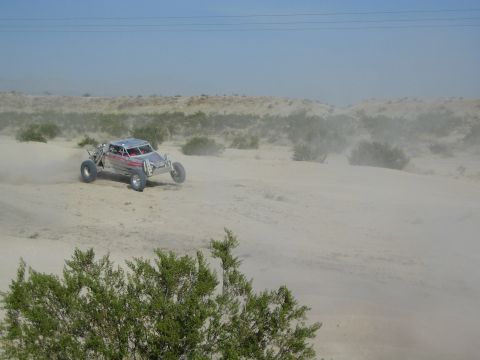 Silver and red off-road buggy racing across dusty desert sand