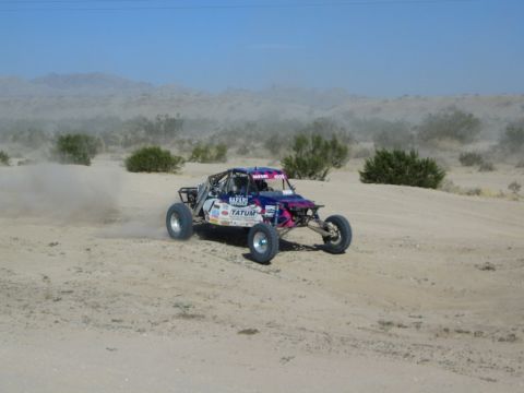 Pink and purple sponsor-decaled race buggy on desert course