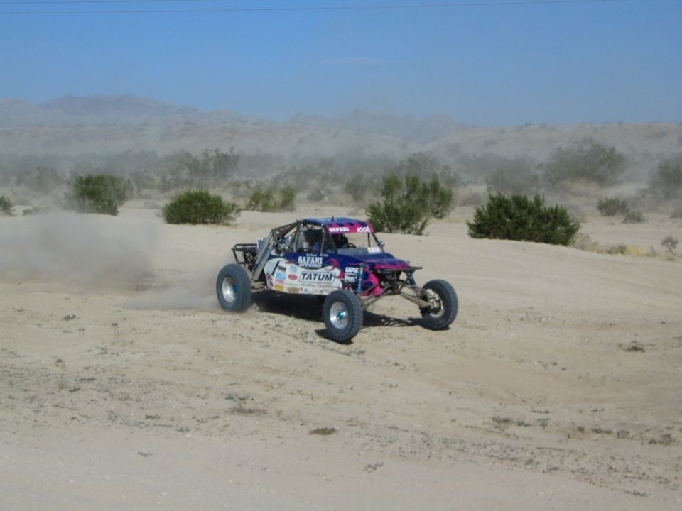 Pink and purple sponsor-decaled race buggy on desert course