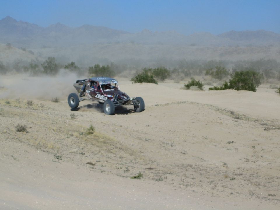 Dark purple off-road race buggy cresting a desert rise