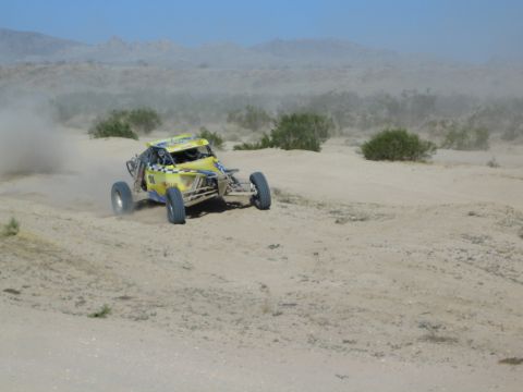 Yellow off-road race buggy carving through desert sand