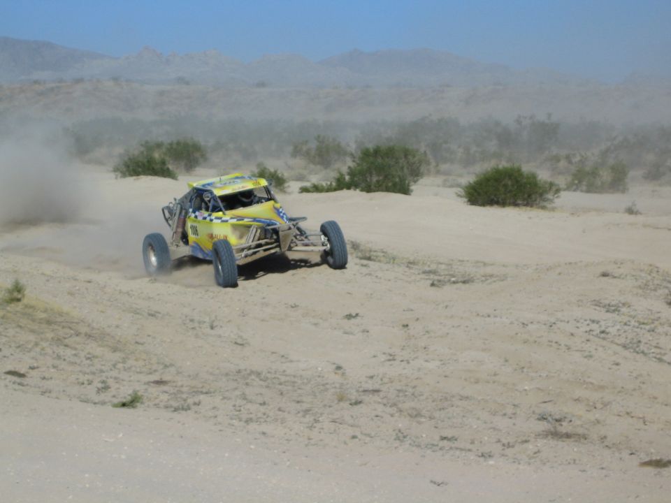 Yellow off-road race buggy carving through desert sand