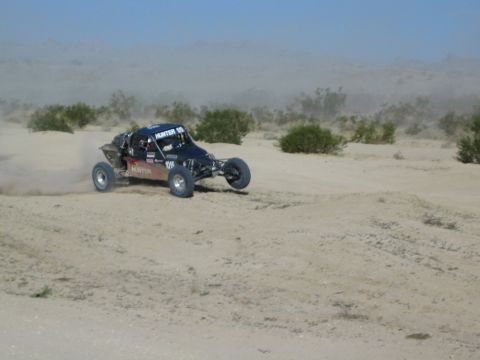 Dark blue Hunter race buggy carving through desert sand