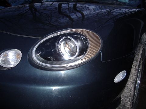 1998 Ford Taurus - Close-up of the front headlight and turn signal assembly on a dark green 1998 Ford Taurus.