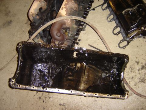1992 Ford Bronco - Engine oil pan and associated parts covered in thick, black sludge.