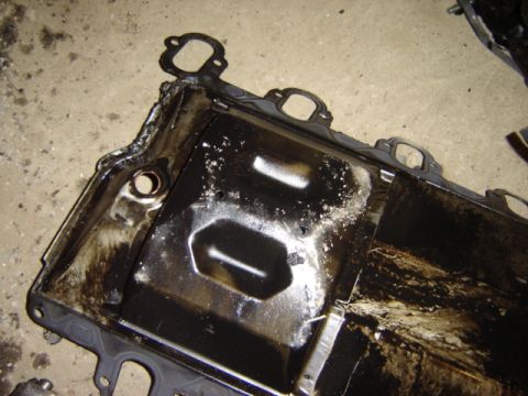 1992 Ford Bronco - A heavily soiled oil pan with visible gasket material and oil residue.