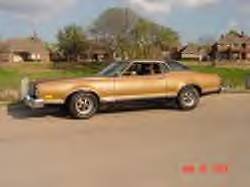 1972 Ford Ranchero - A gold 1972 Ford Ranchero coupe utility is seen from the side, parked outdoors with houses in the distance.