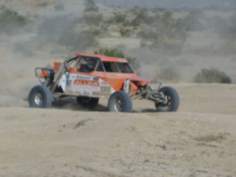 Orange All In number 1003 race buggy on a desert course