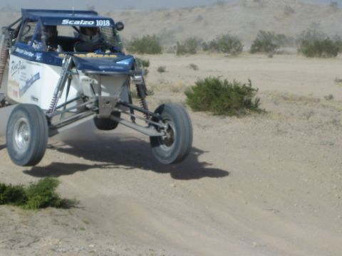 Blue and silver Scalzo 1018 Goodyear race buggy jumping in the desert