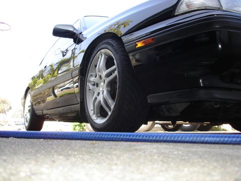 1989 Mazda MX-6 - Close-up of the front passenger side wheel and fender of a black 1989 Mazda MX-6.